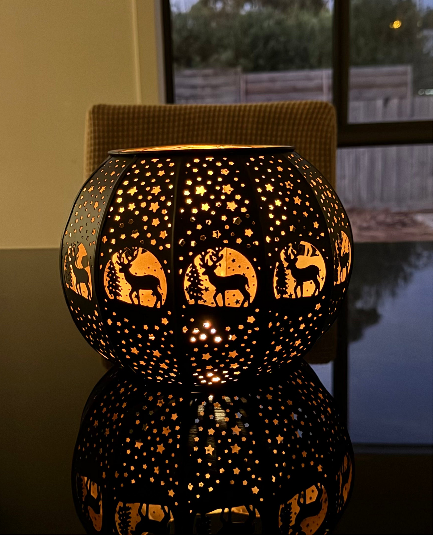 Brass candle lampswith intricate etchings, displaying a warm glow, placed on a surface near a window.